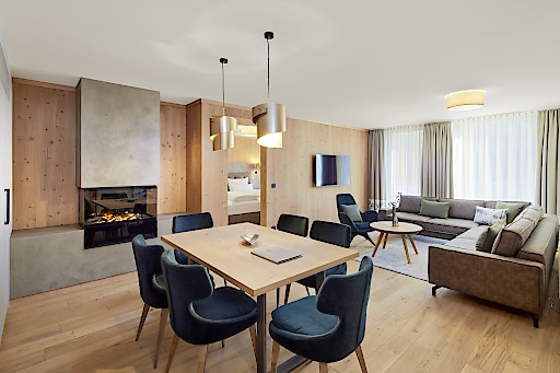 4 Sterne Superior für das neue Zugspitz Resort Neues Zimmer im Zugspitz Resort mit Kamin, Esstisch mit 6 Stühlen, großem Ecksofa und Flachbildfernseher an der Wand