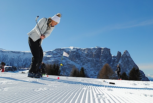 Wintergolfen auf der Seiser Alm Frau auf Schneegolfbahn beim Abschlag