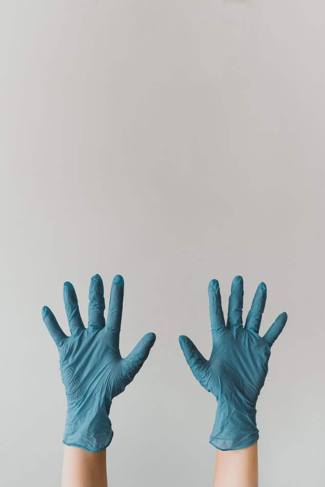 Hände mit blauen sterilen Handschuhen